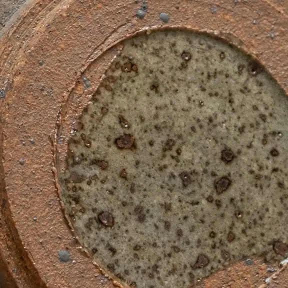 Detalhe da tampa, com pintas escuras e borda sem esmalte