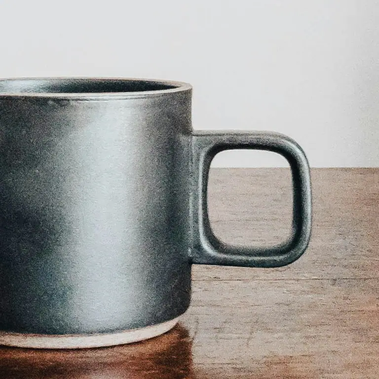 A caneca preta de perto, com a alça quadrada