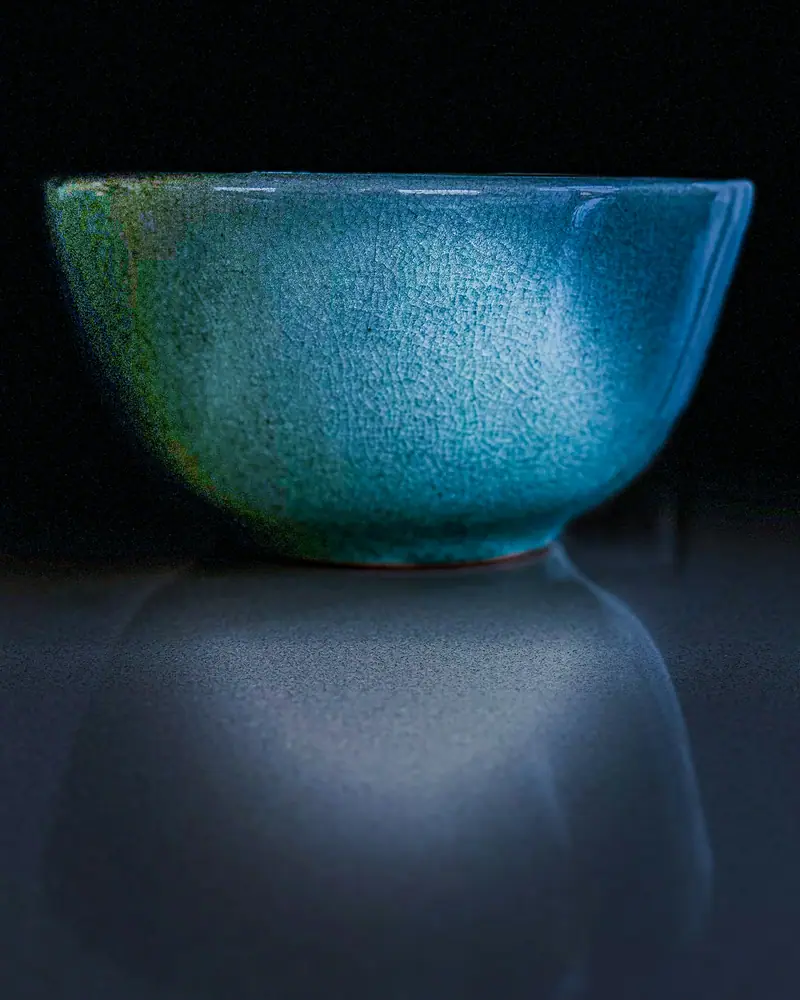 Tigela funda azul sobre superfície escura que reflete a peça