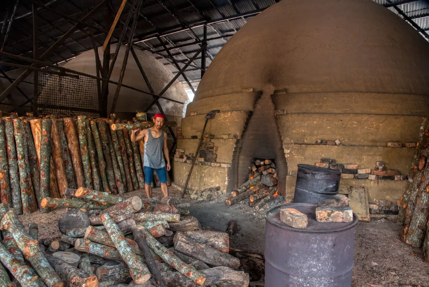 Forno de tijolo em forma de cúpula com toras de lenha empilhadas na frente